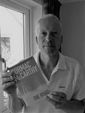 Paul Harwood holding a copy of The Road